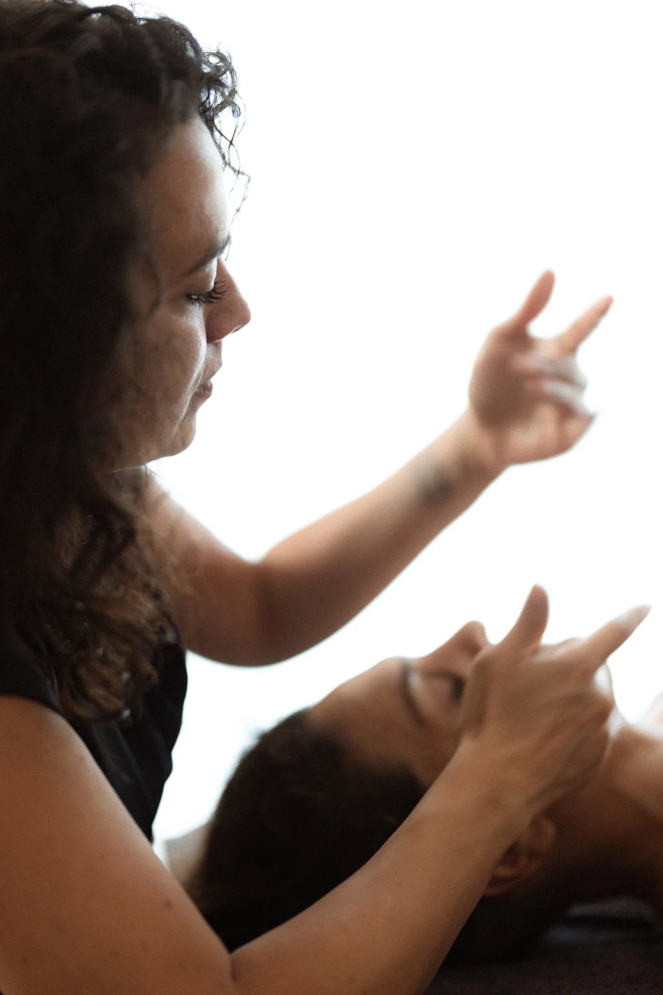 Orianne en posture d'écoute, mains attentives au-dessus du visage d'une personne en séance