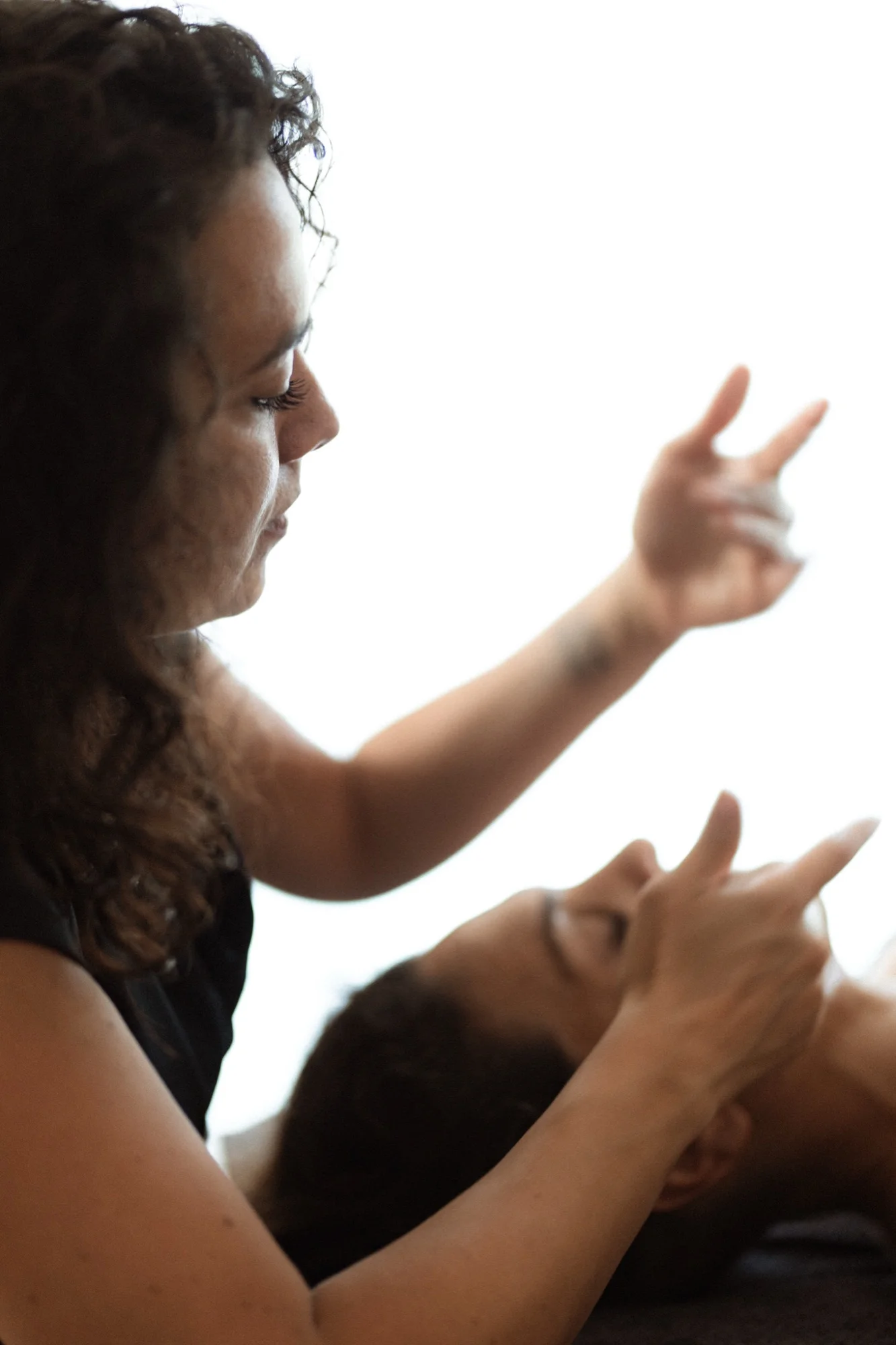 Orianne en posture d'écoute, mains attentives au-dessus du visage d'une personne en séance